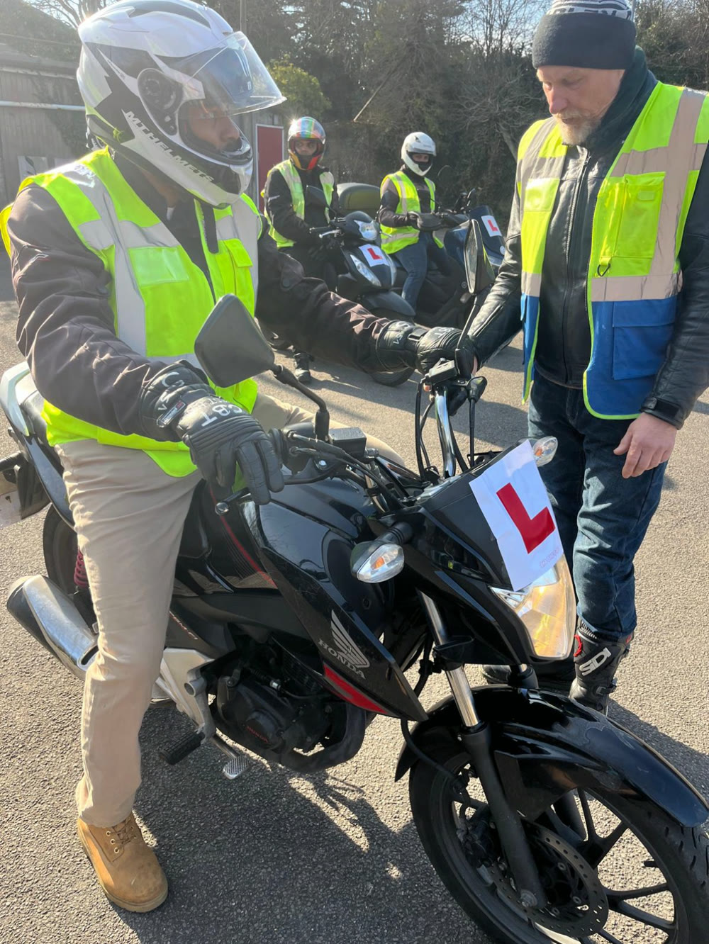 Instructor with a rider on a bigger bike during an assessment